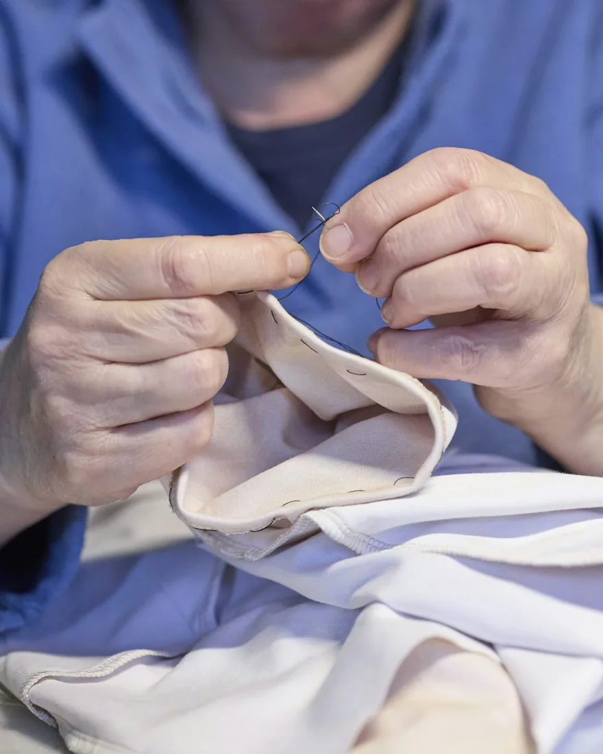 Detail rukou při ručním šití látky jehlou a nití
